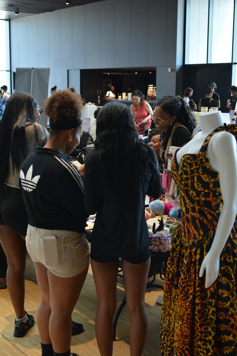 People in a room with a mannequin wearing a patterned dress.