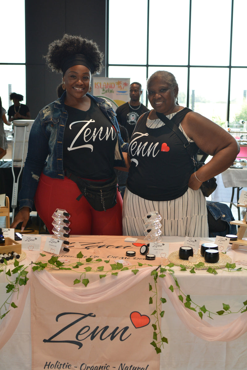 Two women standing behind a table with 'Zenn' branding at an event.