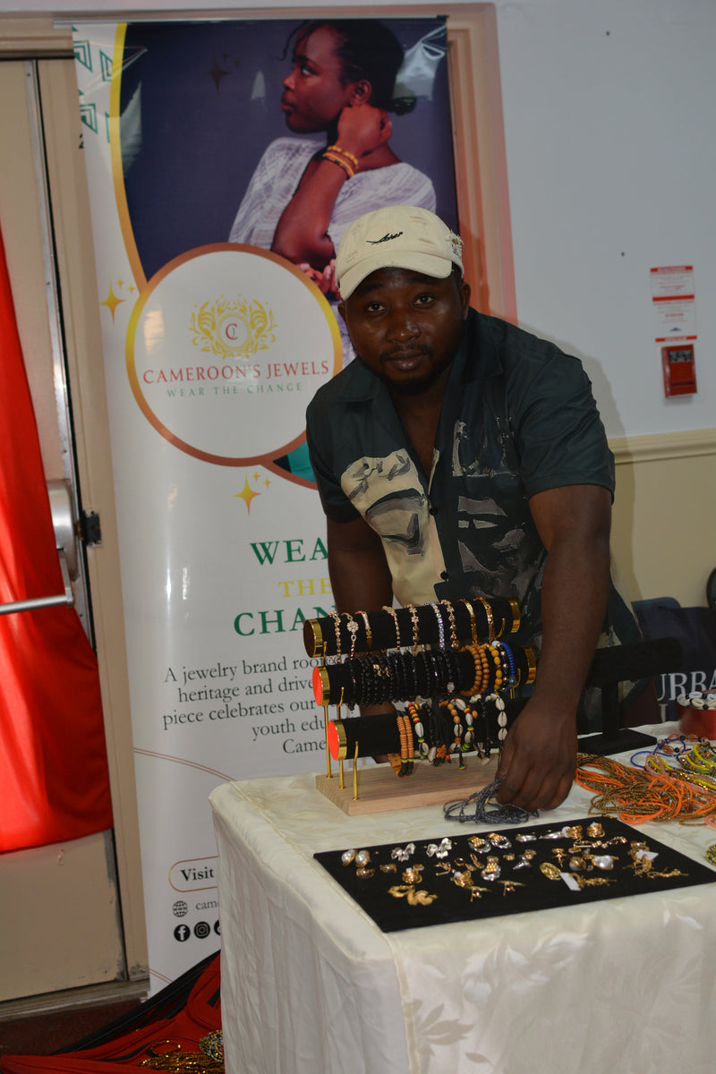 Man displaying jewelry at a table with a poster in the background