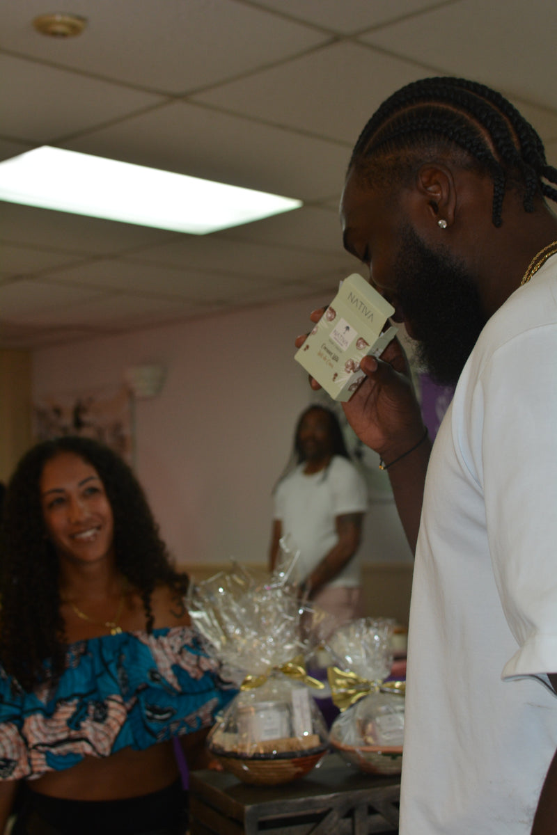 Man smelling soap with a woman smiling in the background