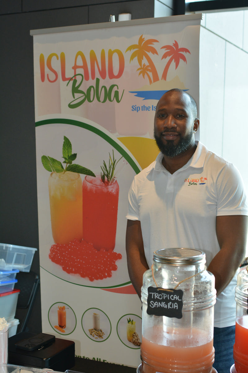 Person holding a bottle with a 'Bubly' label in front of an Island Bubly promotional banner.