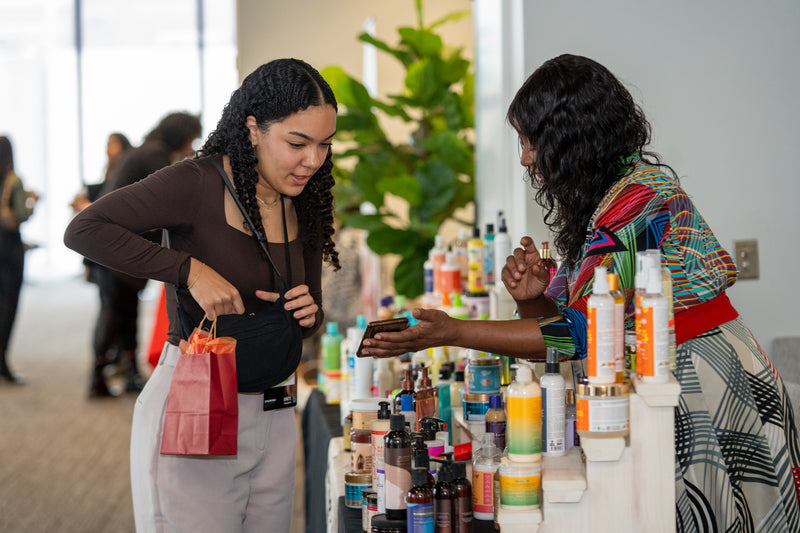 Two women interacting with a display of skincare products in a store.