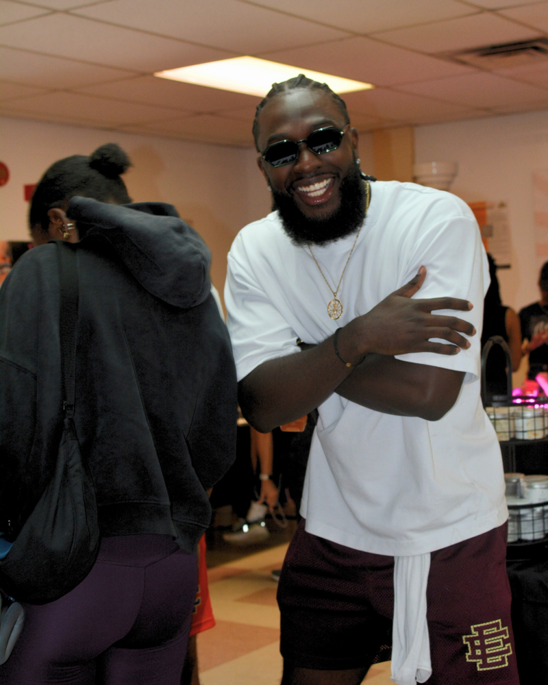 Man in a white shirt and sunglasses smiling in a casual indoor setting