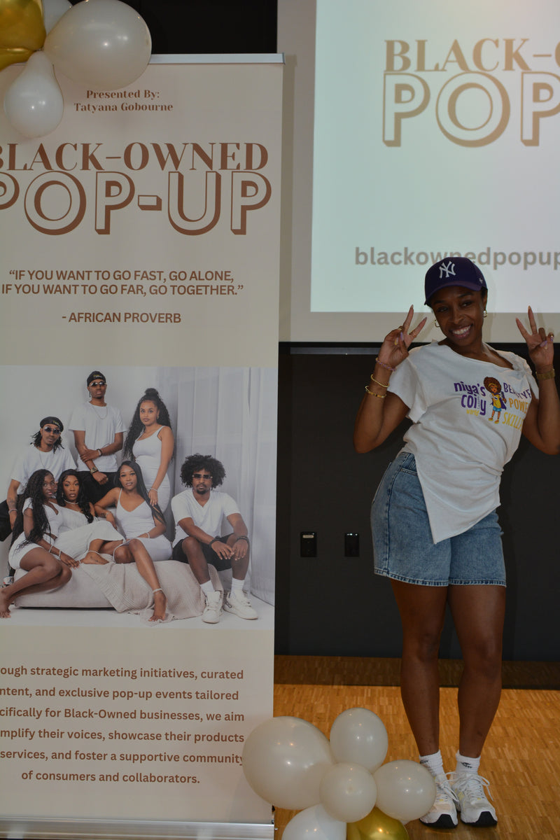 Woman standing in front of a 'Black-Owned Pop-Up' event banner with balloons.