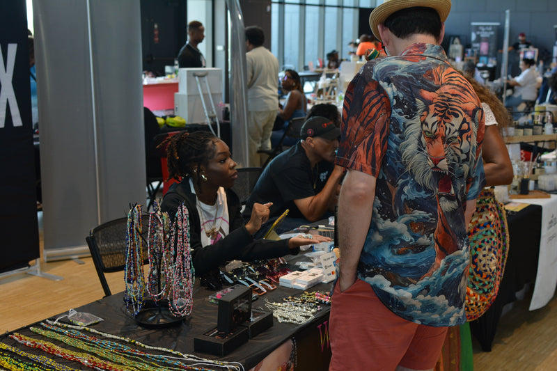 Person with a colorful tiger design on their back at a market stall with jewelry.