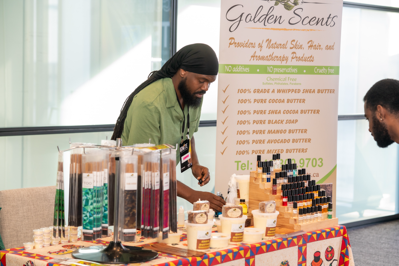 Person interacting with a display of products at an event with 'Golden Scents' branding.