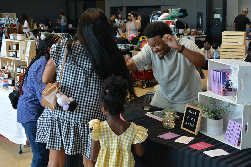 Family interacting with a magician at a booth in a lively indoor setting